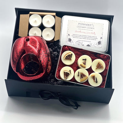 Gift set with red diffuser, candles, and a card in a black box.