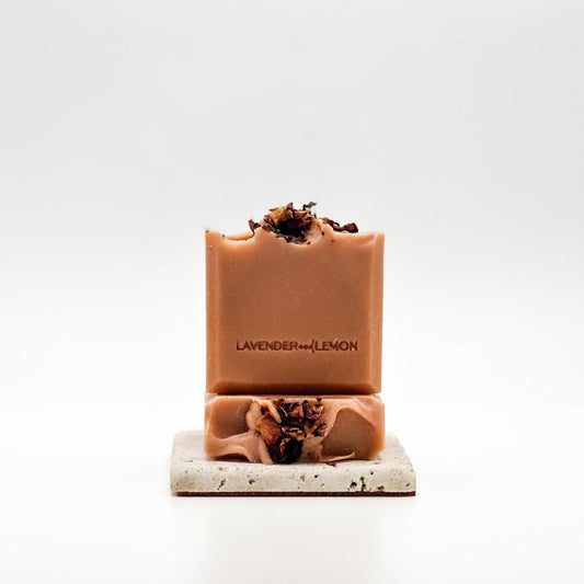 Two bars of organic gernaium and bergamot soap with dried herbs on a white background, branded 'Lavender & Lemon'. Vegan. Palm free.