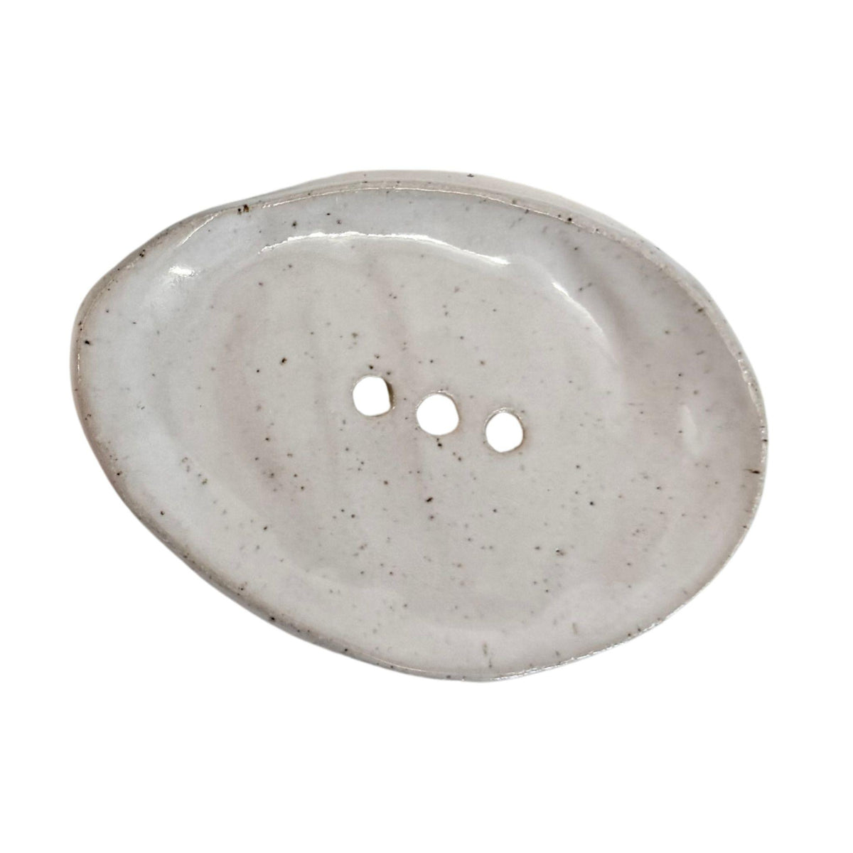 An organic-shaped ceramic dish with three holes, featuring a speckled off-white glaze on a solid white background.
